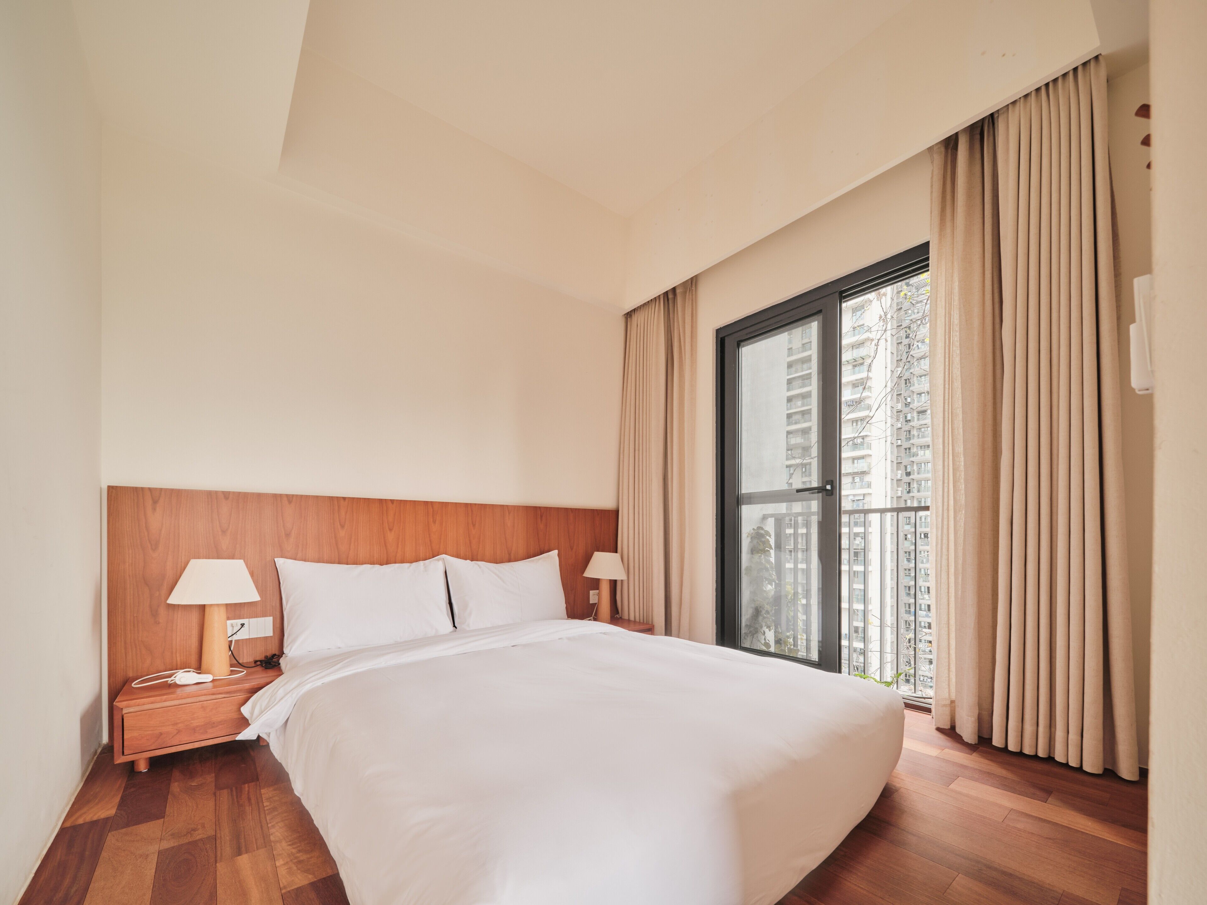 Ein Hotelzimmer mit einem großen Bett, einem hölzernen Kopfteil, zwei Nachttischen mit Lampen und einem Fenster mit Vorhängen.
