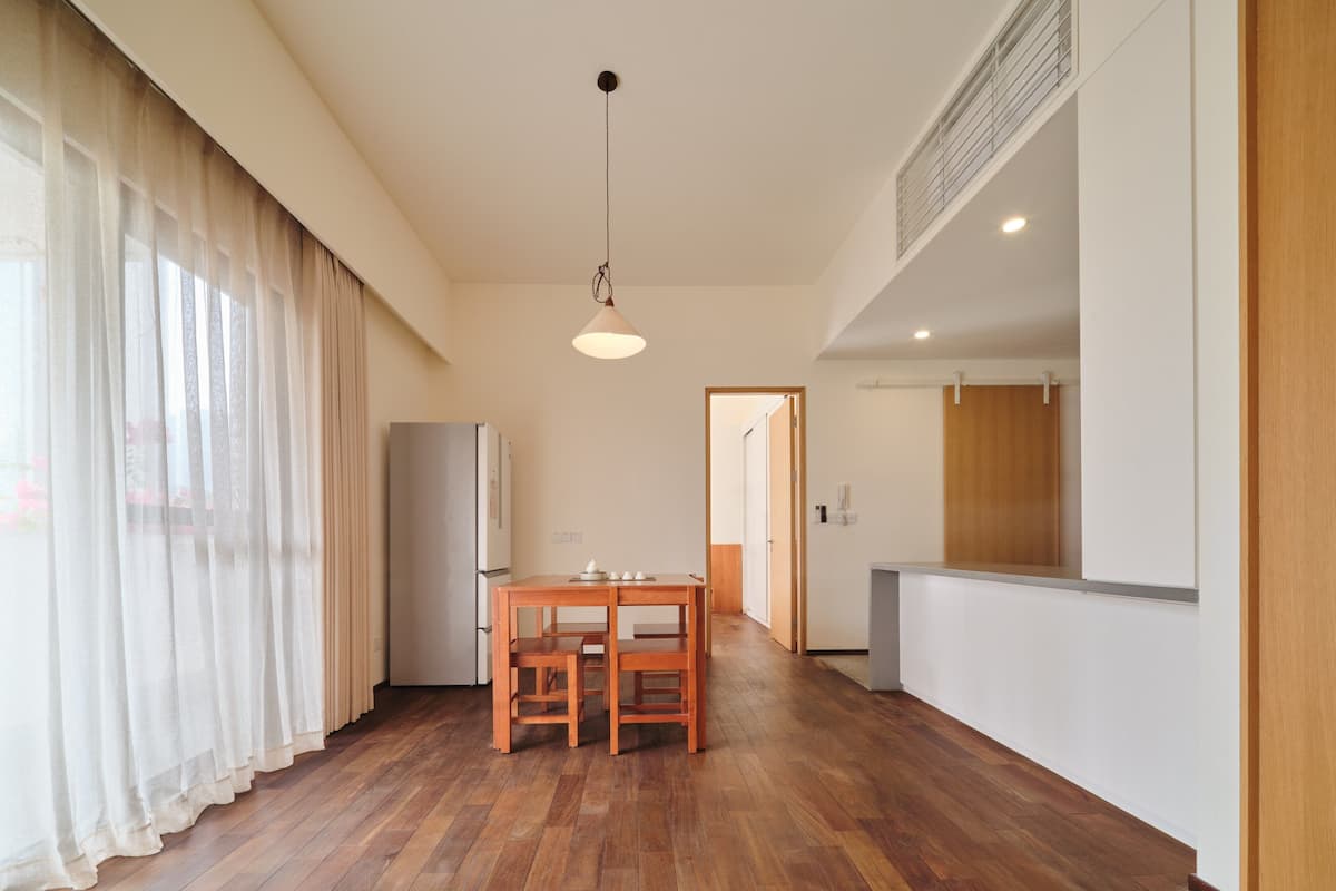 Eine moderne Küche mit Holzboden, einem Esstisch mit Stühlen und einem Kühlschrank.