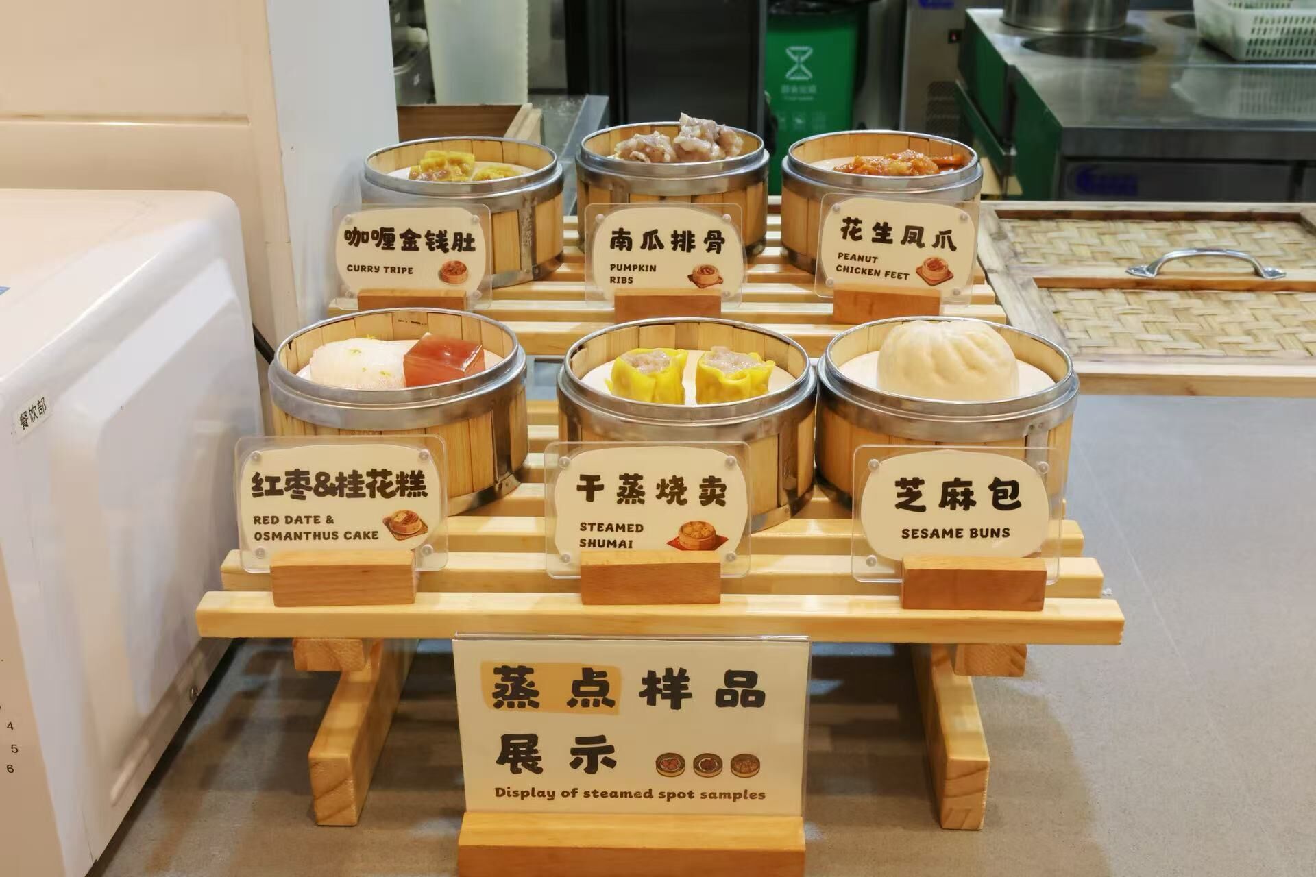 A display of various steamed food items in bamboo containers with labels in a food establishment.