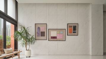 A modern interior with a large window, a potted plant, and three framed artworks on the wall.