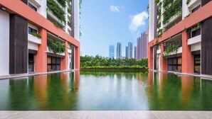 A modern building with a central pool, surrounded by greenery and high-rise buildings in the background. - Wutong Hotel Apartment (Bao'an Center) (Shenzhen)