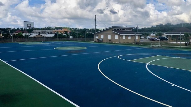 Una cancha de baloncesto al aire libre con un edificio al fondo.