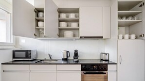 Une cuisine moderne dotée de meubles blancs, d’un four à micro-ondes, d’une bouilloire, d’un grille-pain et d’un lave-vaisselle.