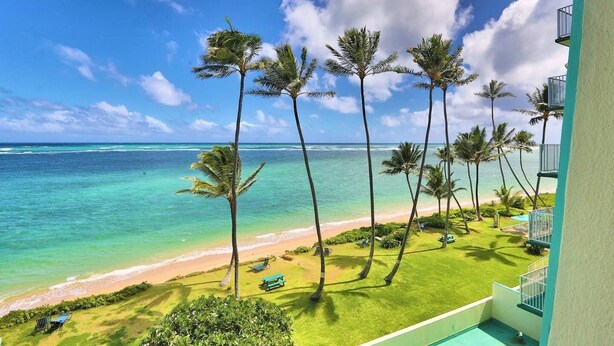 Ein Strandgrundstück mit Pool, Palmen und Meerblick.