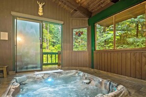 Una cabaña de madera con jacuzzi, ventanas amplias y una decoración de cabeza de ciervo.