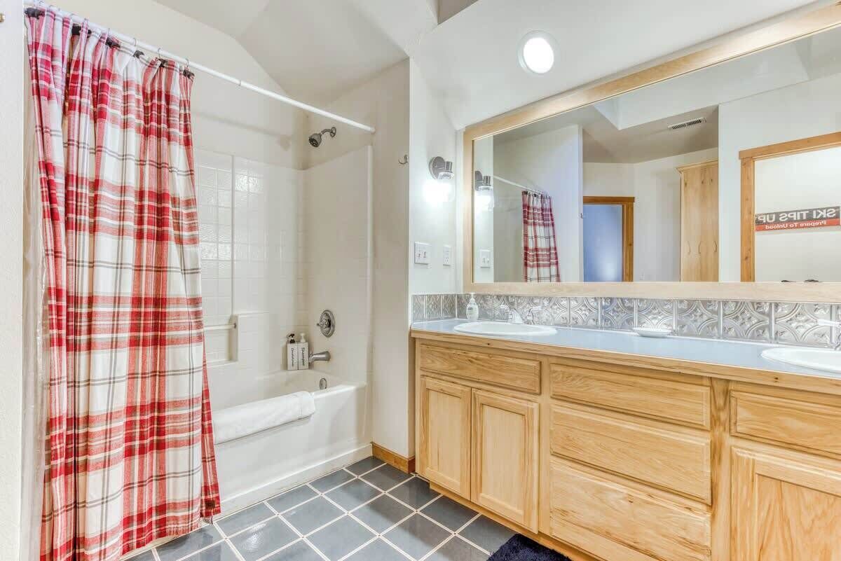 A bathroom with a shower, a bathtub, a vanity with a mirror, and a tiled floor.