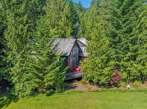 A cabin surrounded by dense forest, with a deck and outdoor seating area.