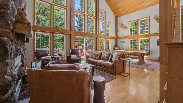 Un salón amplio con chimenea, ventanas grandes y mesa de billar.