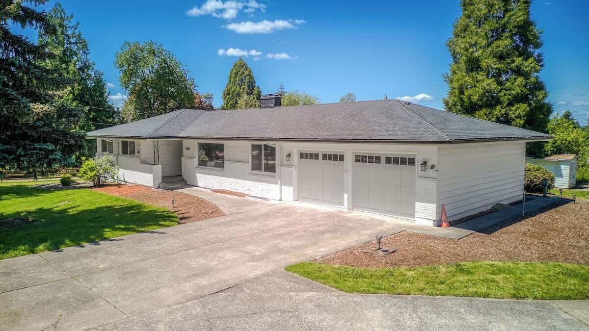 Una casa a un piano con garage, portico e vialetto.