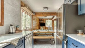 Une cuisine moderne avec une table à manger en bois, des placards intégrés et de grandes fenêtres.