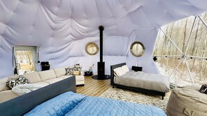 Um interior acolhedor com um sofá, uma cama, uma mesa redonda e uma estrutura de teto incomum em forma de tenda.