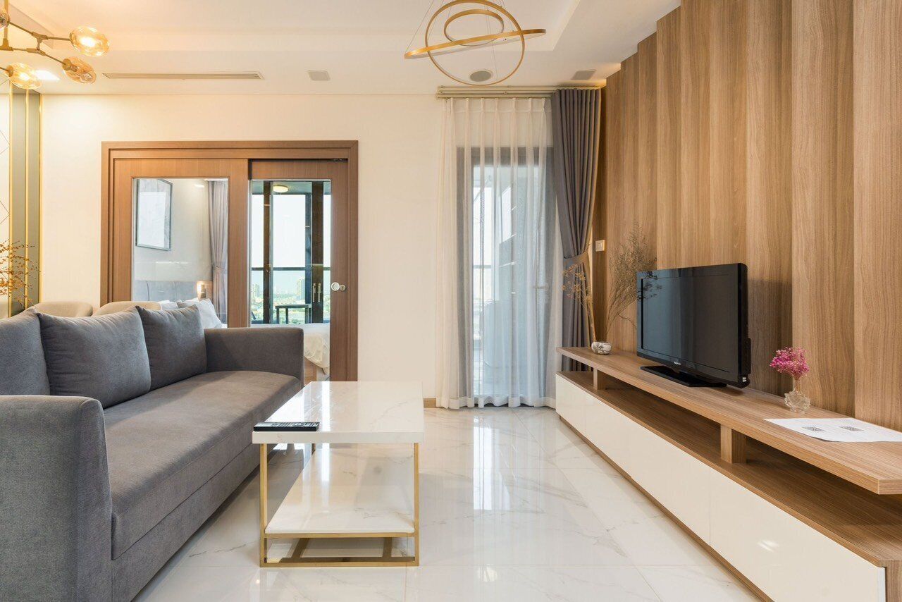 A modern living room with a sofa, coffee table, TV, and wooden paneling.