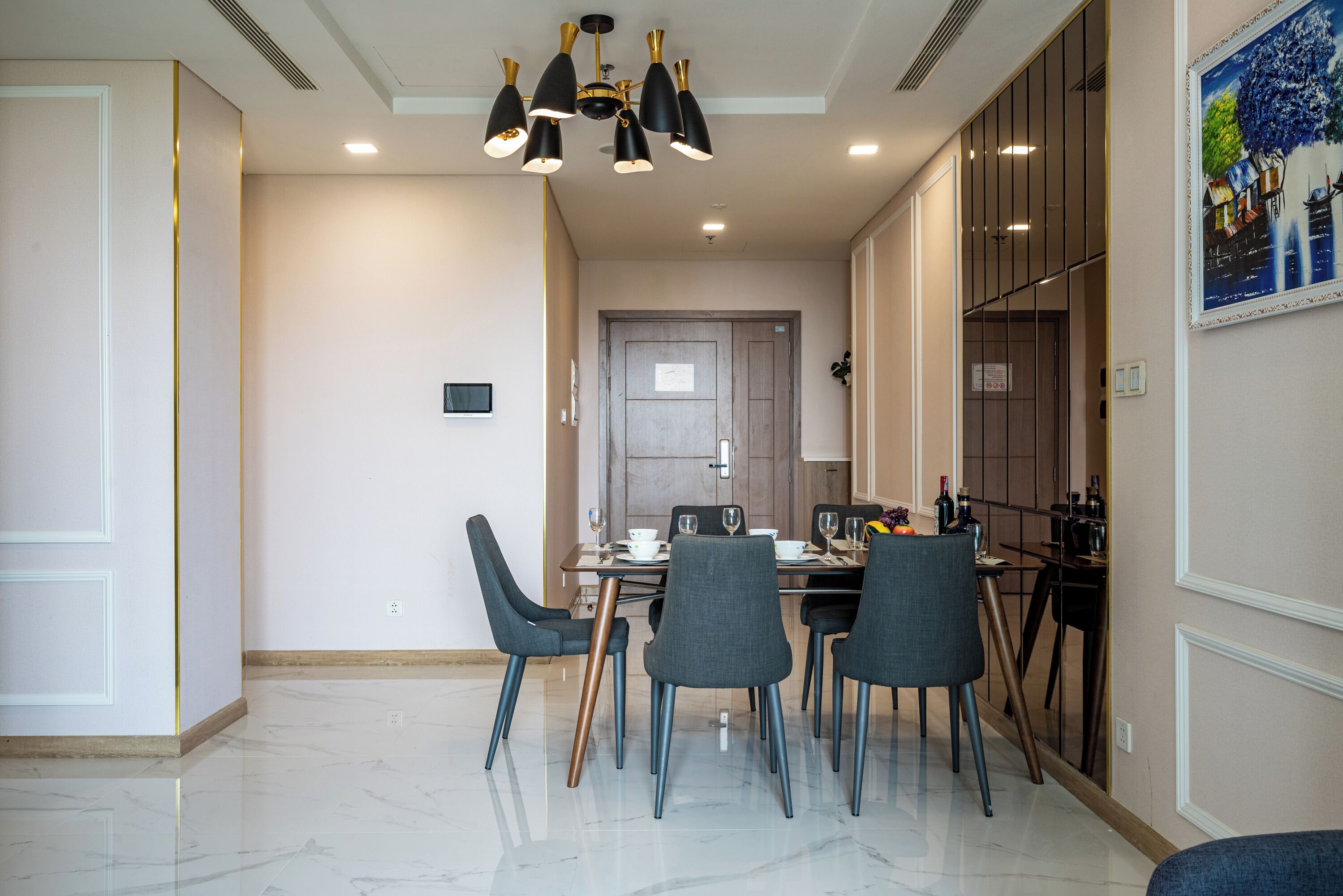 Un comedor con piso de mármol, sillas modernas y una araña.