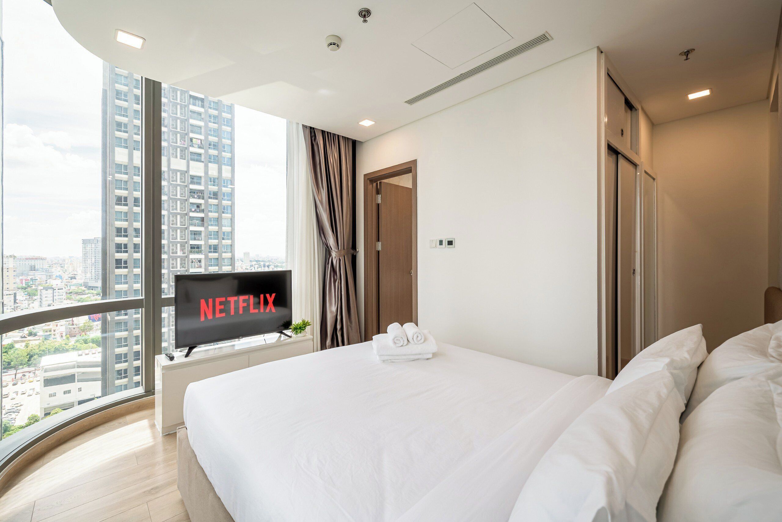 Une chambre d’hôtel moderne dotée d’un grand lit, d’une télévision et offrant une vue sur la ville.