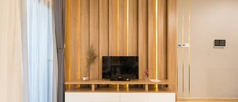 Uma sala de estar moderna com uma TV de tela plana sobre um móvel de madeira, uma mesa de centro de mármore e um controle remoto na mesa.