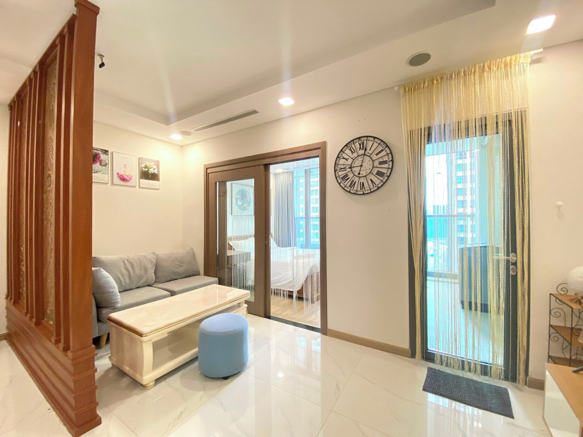A modern living room with a sofa, ottoman, and a wall clock.
