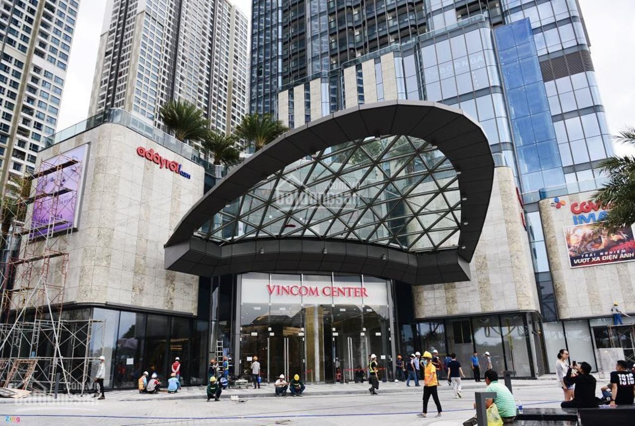 Exterior del edificio Vincom Center, con una amplia entrada de vidrio y edificios altos circundantes.