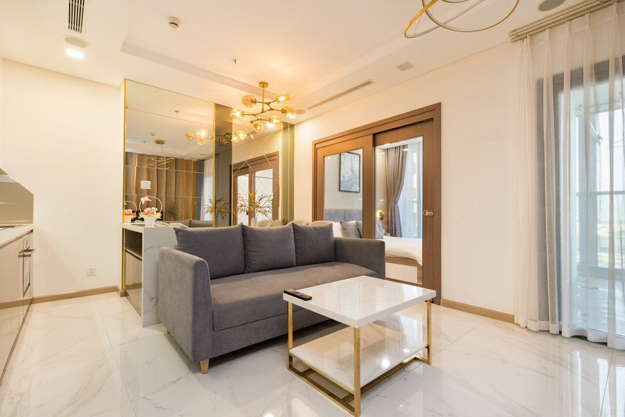 A modern living room with a grey sofa, a white coffee table, and a large mirror.