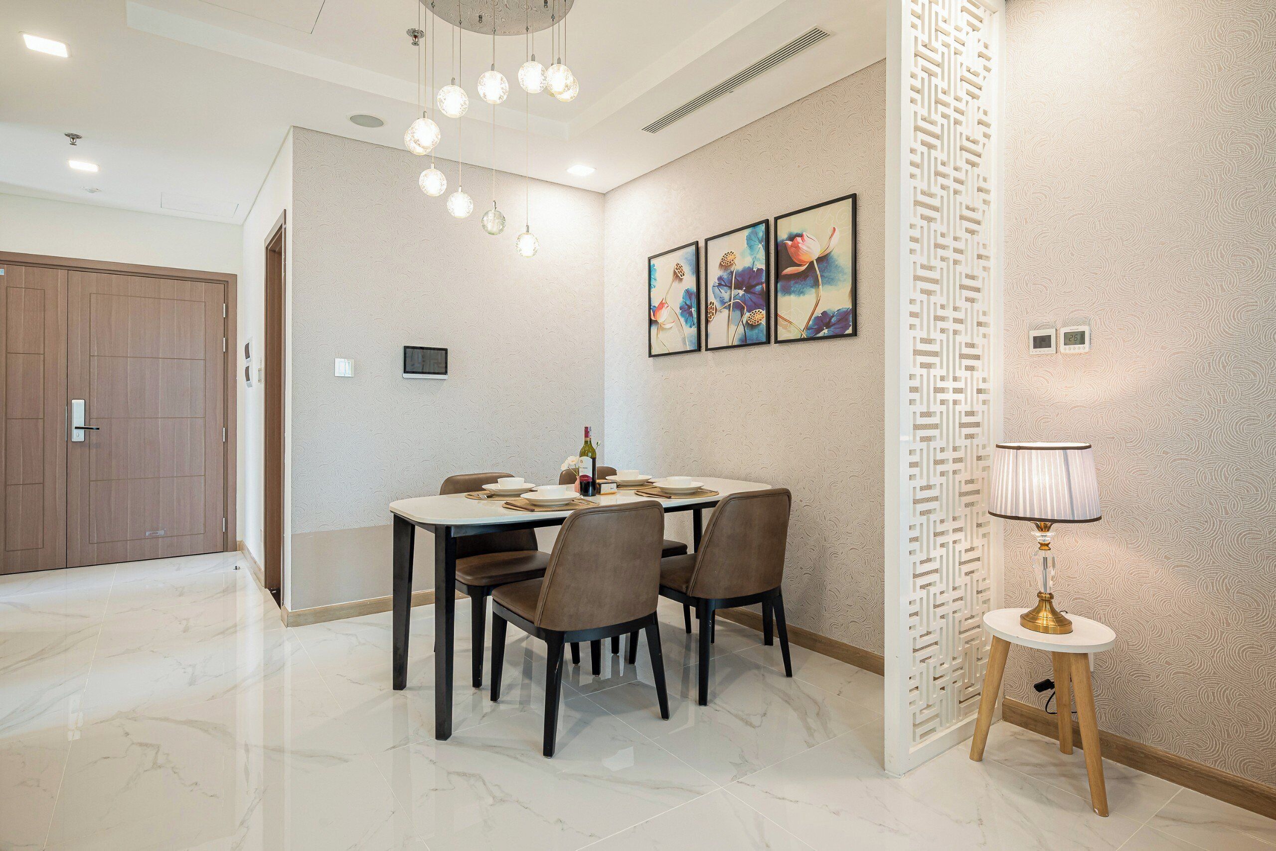 A dining area with a marble floor, a round table with chairs, and a wall-mounted light fixture.