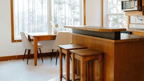 A modern kitchen with a wooden island, white chairs, and a large window. - Steps from the lift, quick pedal to the trails, short drive to golf.  (Kimberley)