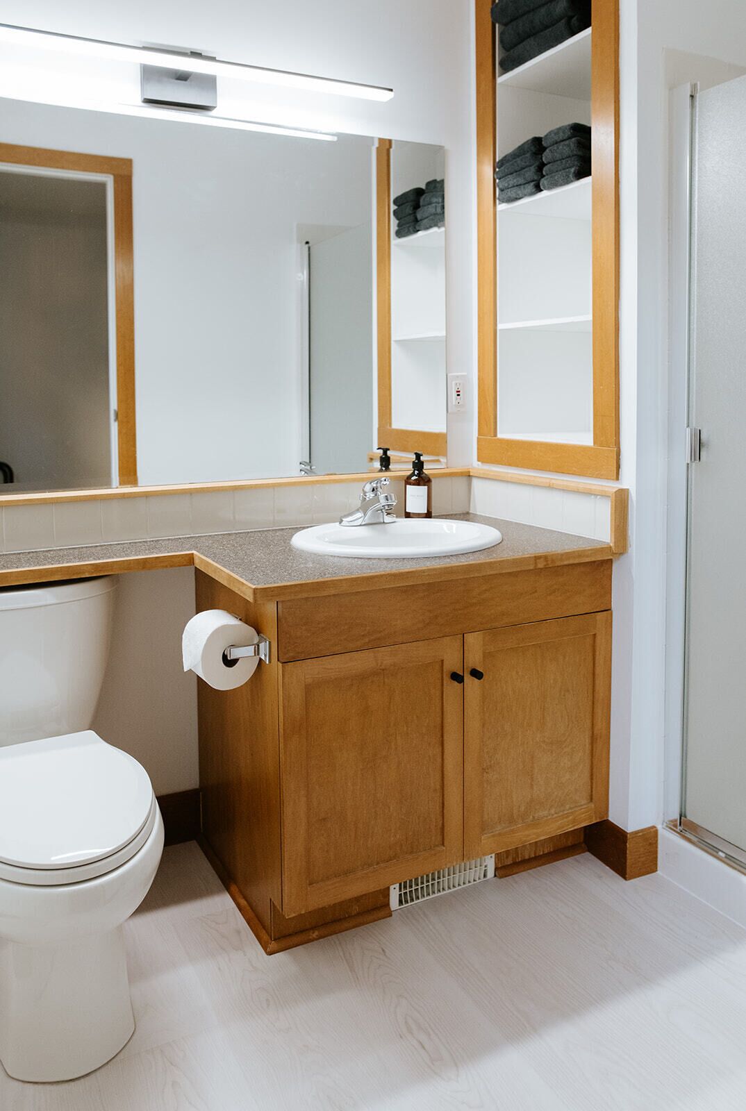 A bathroom with a wooden vanity, white sink, and a toilet.