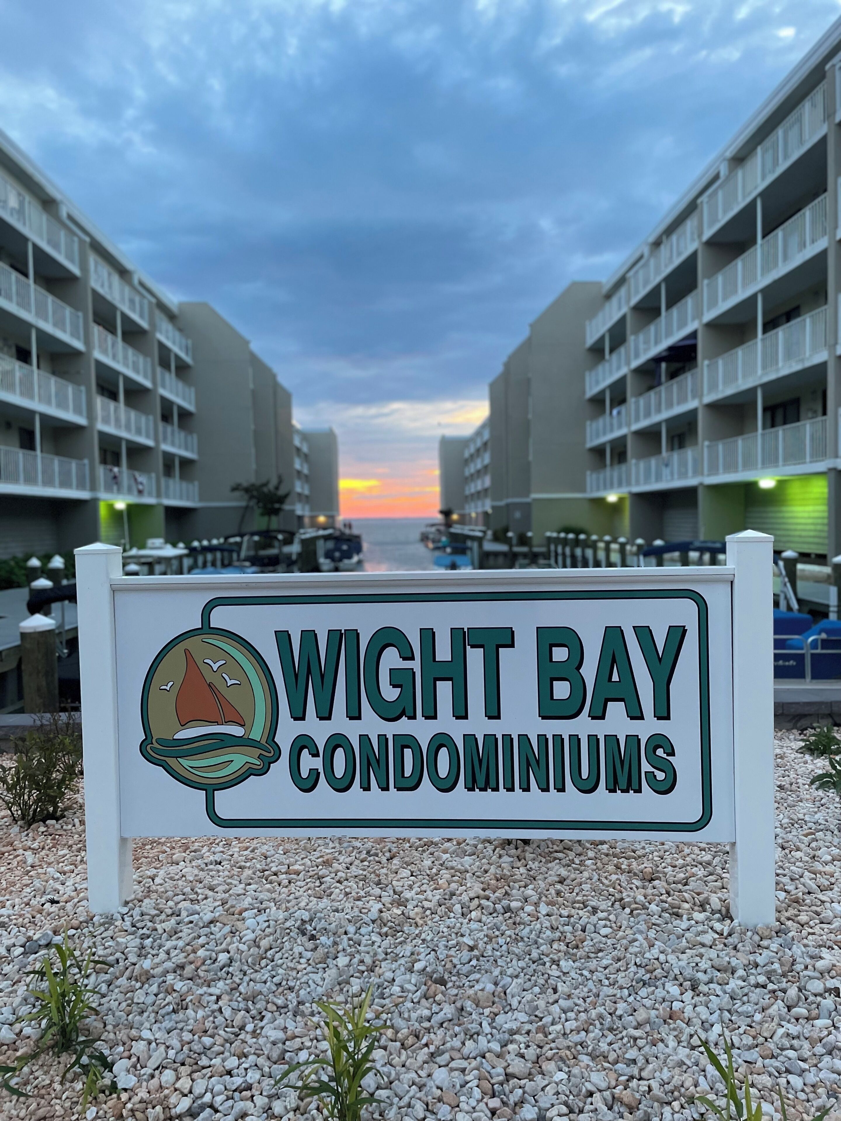 Placa para Wight Bay Condominiums, vista do oceano e pôr do sol ao fundo.