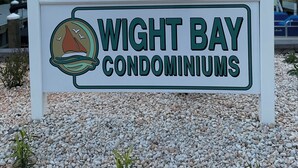 Señal de Wight Bay Condominiums con vista al océano y un atardecer de fondo.
