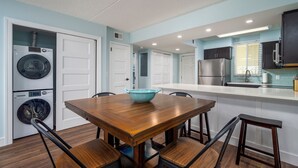 Una cocina compacta con una mesa de comedor de madera, sillas y lavadora y secadora integradas.