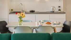A modern kitchen with a dining table set for two, a coffee machine, and a vase with flowers. - Picigin by Interhome (Zadar/Bibinje)