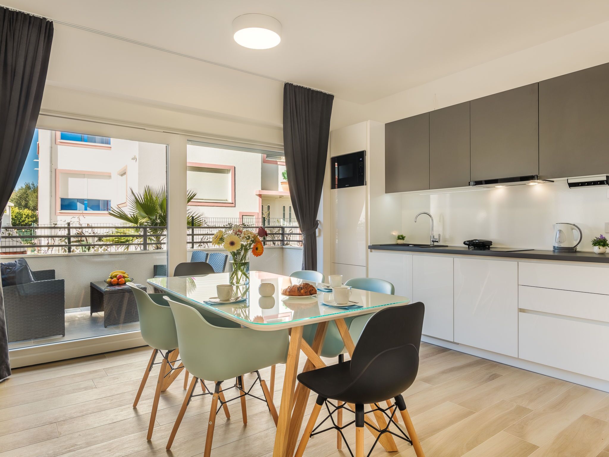 Una cocina moderna con armarios blancos, un microondas negro y una tetera sobre la encimera.