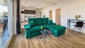 A modern living room with a green sofa, a small table with drinks, and a kitchen in the background. - Picigin by Interhome (Zadar/Bibinje)