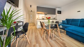 Ein modernes Wohnzimmer mit einem Glastisch, einem blauen Sofa und Holzböden.