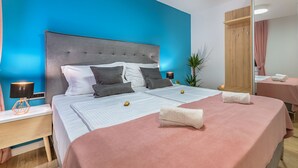 Ein modernes Hotelzimmer mit einem großen Bett, zwei Nachttischen, einem Schminktisch und einem Blumentopf.
