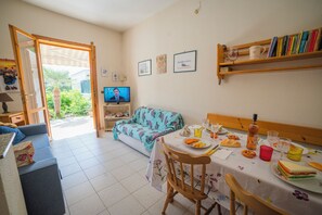 A dining area with a table set for two, a television, and a sofa.