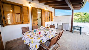 A covered patio with a dining table set for four, wooden shutters, and a view of the outdoors. - Villetta Tesea In Residence Near The Sea, Melendugno, Italy (Melendugno)