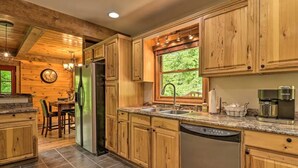 A kitchen with wooden cabinets, a refrigerator, a dishwasher, a sink, and a coffee maker. - Woodfern Retreat-Pet Friendly EasyCentral Location (Maggie Valley)