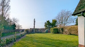Ein Garten mit Rasen, einem Zaun, einem Strommast und einem Gebäude mit geneigtem Dach.