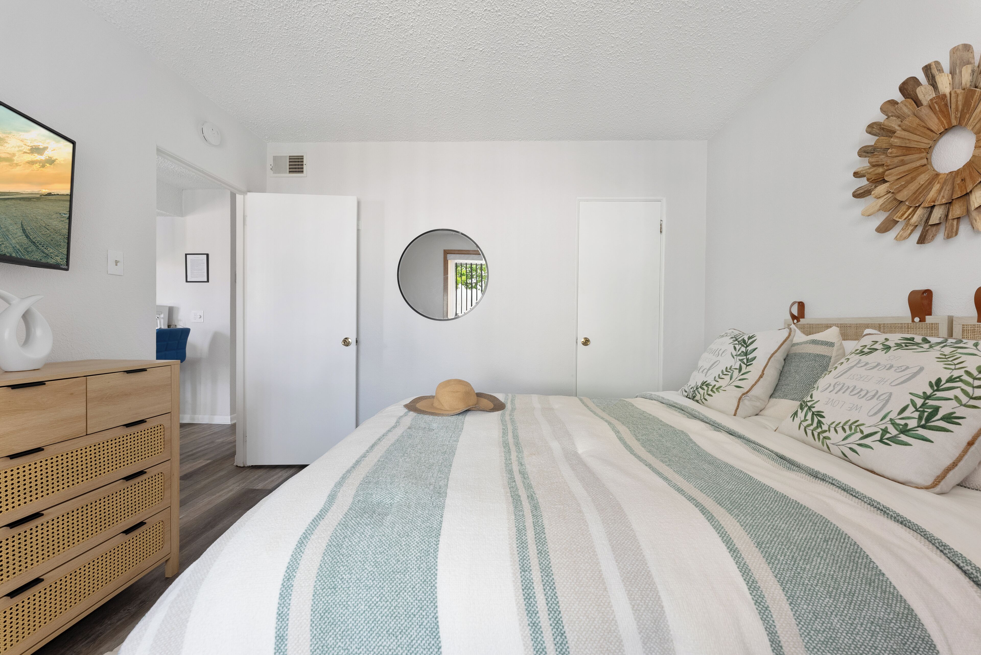 Un dormitorio con una cama, un aparador, un espejo y un adorno en la pared.