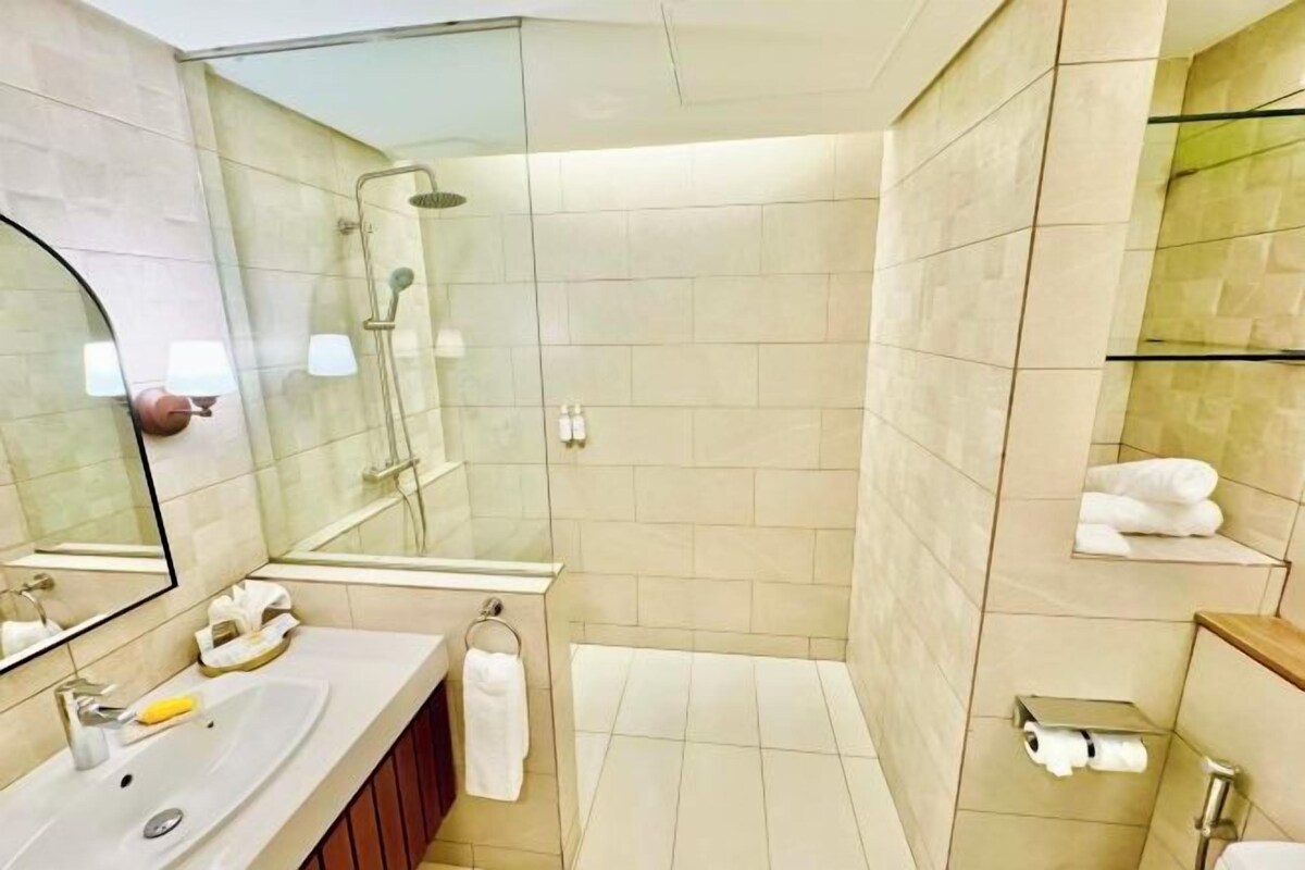 A modern bathroom with a glass shower enclosure, a sink with a mirror, and a towel rack.