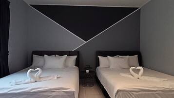Une chambre d’hôtel avec deux lits, chacun agrémenté d’une serviette en forme de cœur, une petite table avec une plante et un plafond au motif géométrique.