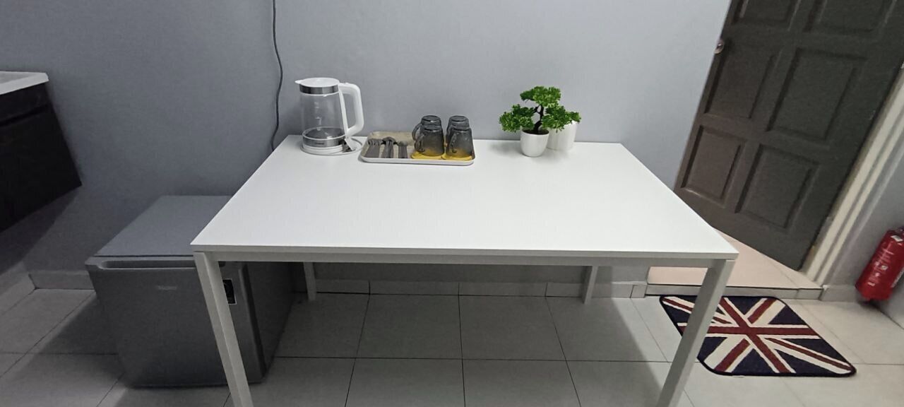 A white table with a kettle, salt and pepper shakers, and a small potted plant.