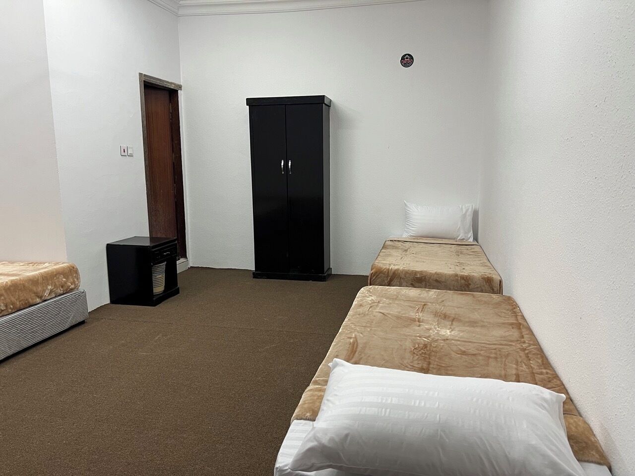 A small, sparsely furnished room with two single beds, a wardrobe, and a heater.