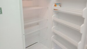 Un refrigerador blanco vacío con varias estantes y una pequeña caja naranja en el estante superior.
