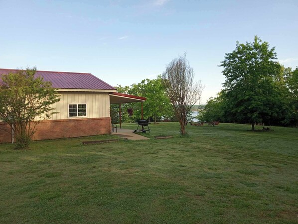 A house with a covered patio, a lawn, and a tree.