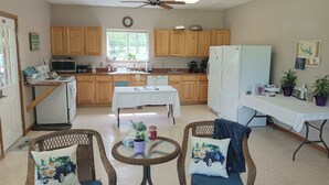 Una cocina compacta con armarios de madera, una mesa de comedor, sillas de mimbre y un ventilador de techo.