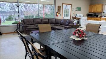 A conference room with a long table, chairs, a ceiling fan, and a view of the outdoors.