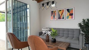 Una sala de estar moderna con un sofá gris, dos sillones de cuero marrón, una mesa de centro de madera y una planta en maceta.