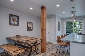 Une cuisine moderne avec une table à manger en bois, des bancs et un îlot central doté de tabourets de bar.
