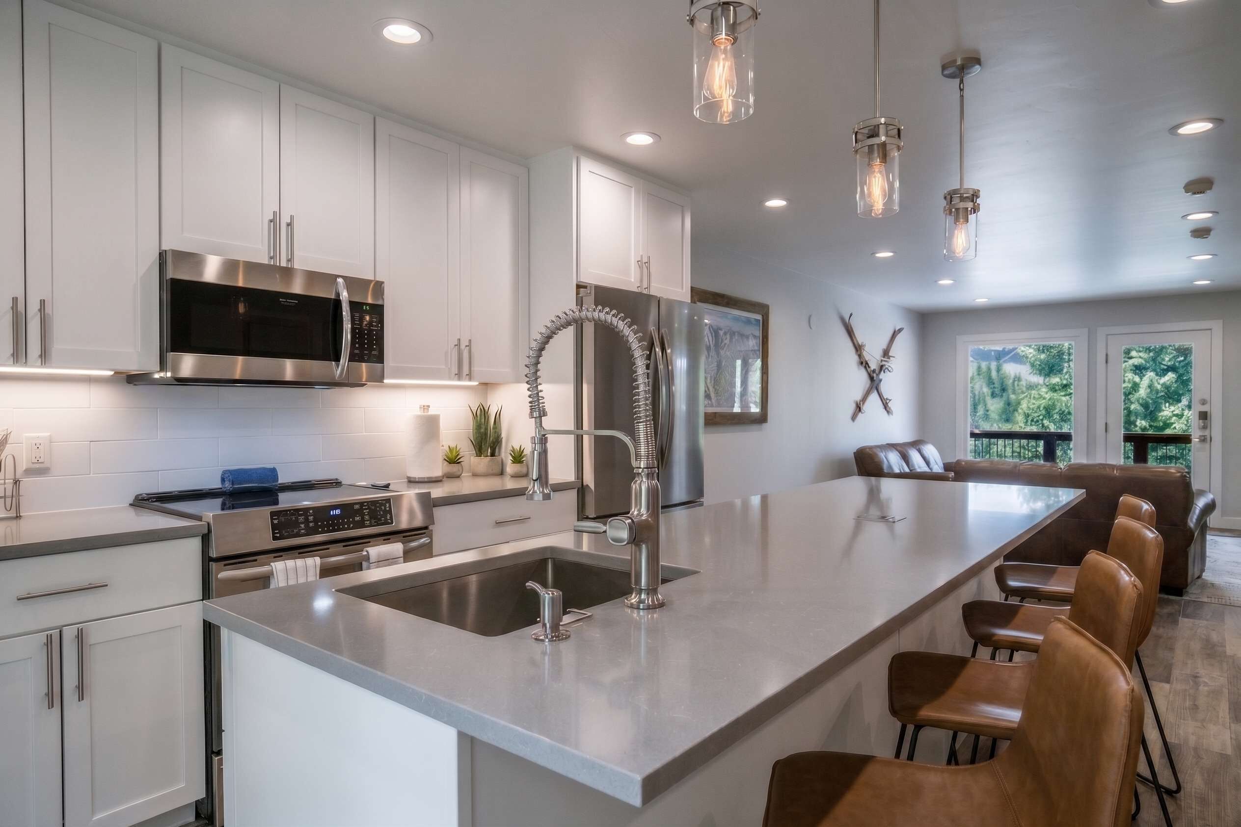 A modern kitchen with stainless steel appliances, a large island with bar seating, and pendant lighting.