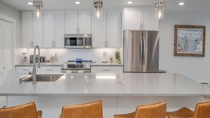 A modern kitchen with white cabinetry, stainless steel appliances, and a central island with bar stools. - 3BR with Mountain Views on FREE Bus Line (Breckenridge)